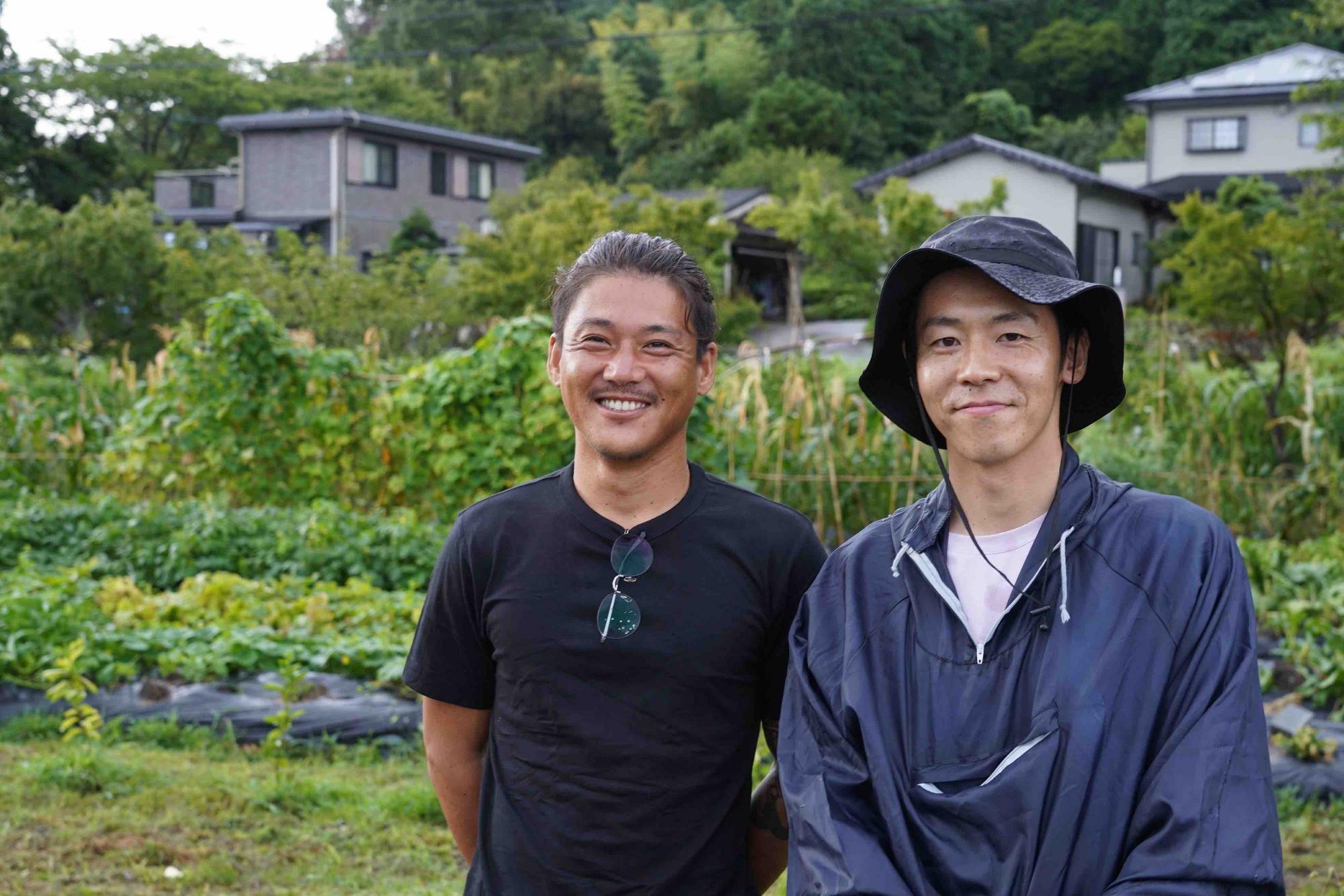 帰人メンバーの安武成晴さん（左）と橋本浩一さん。庭師でもある安武さんは、毎朝仕事の前に水を汲んで畑に水撒きを続けている
