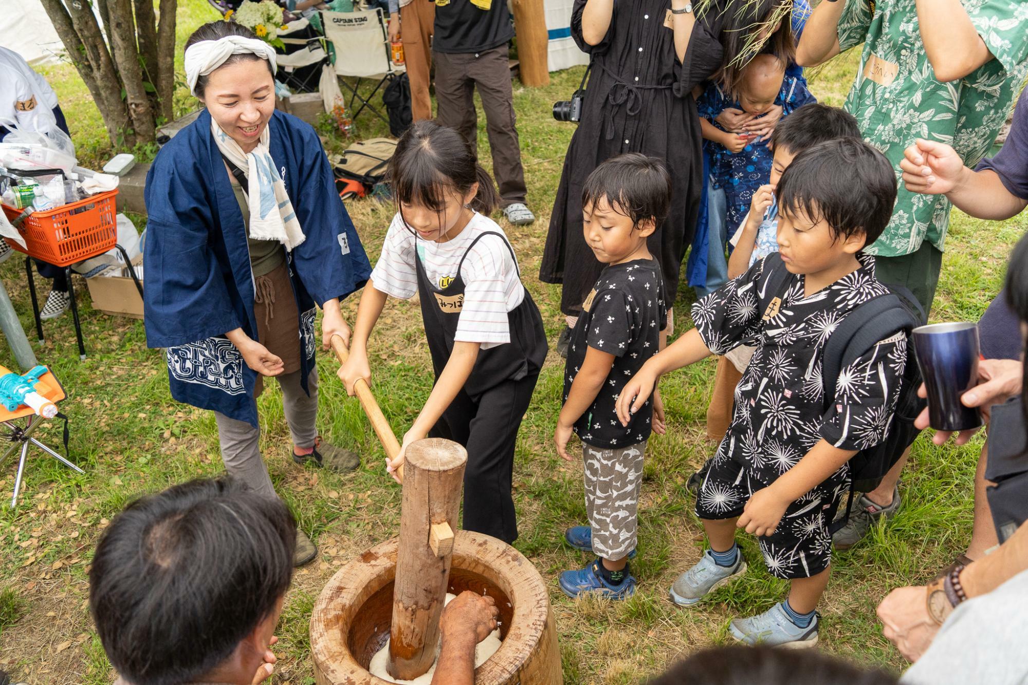 「餅つき始めるよ〜」の声に集まる子どもたち。大人たちにやり方を教えてもらいながら楽しそうに餅つきをしていた