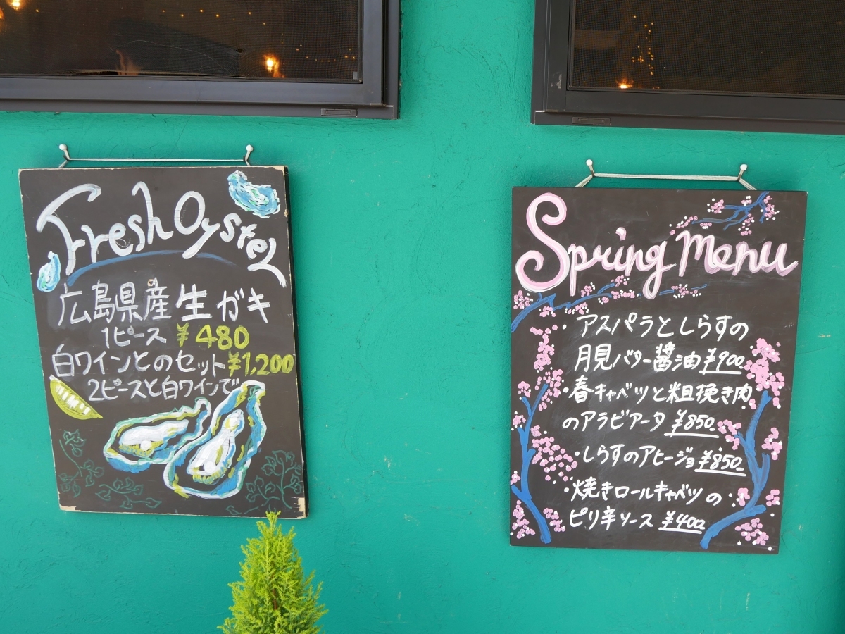 外壁に飾られたスプリングメニューと広島産生牡蠣の手書きの看板