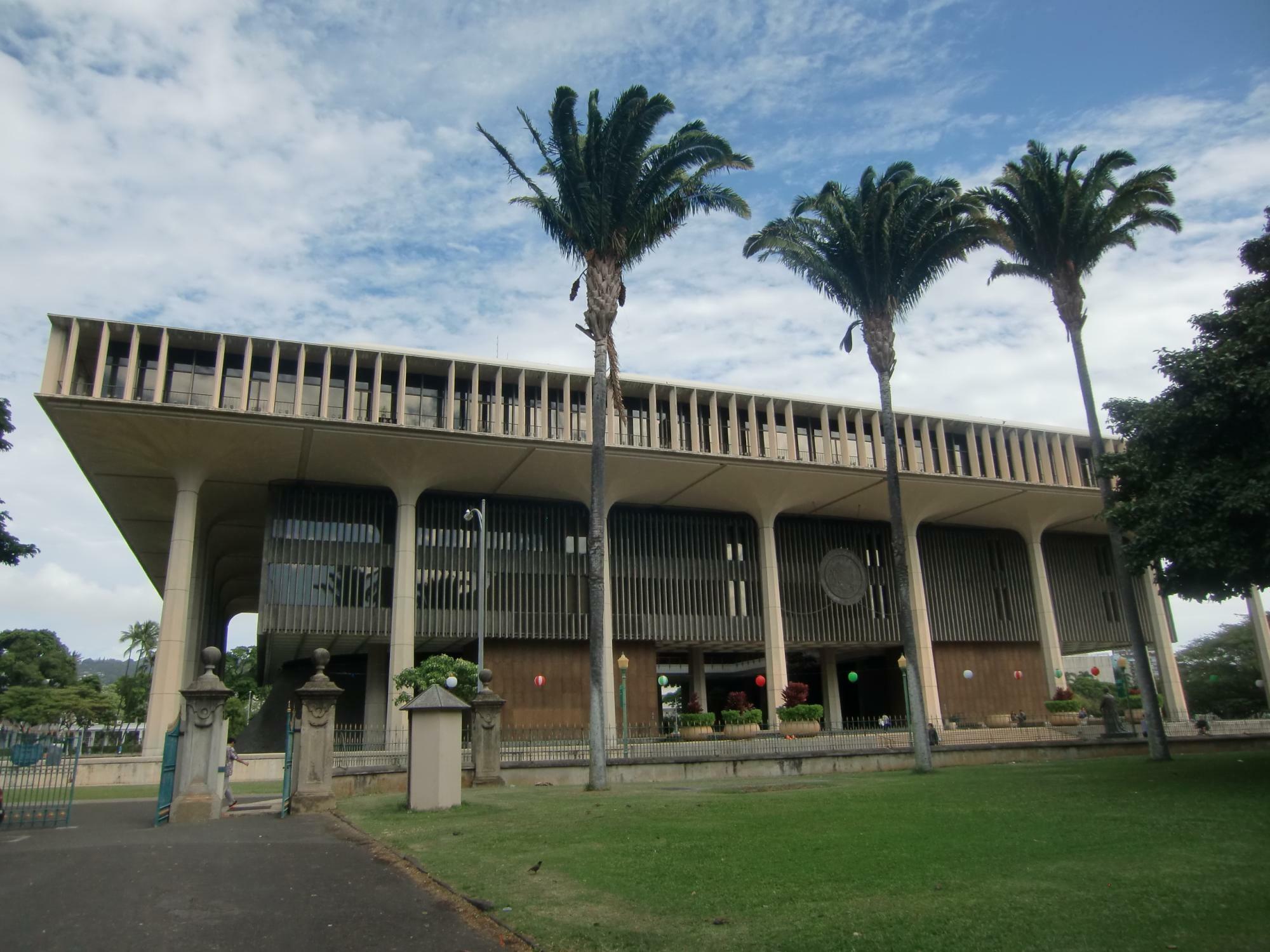 ハワイ州・ホノルル市内、ダウンタウンエリアにあるハワイ州庁舎。州庁舎の建物はハワイ州の自然・文化的な特徴が取り入れられており、椰子の木、太平洋、火山、ハイビスカス等がイメージされた（2014年撮影）。