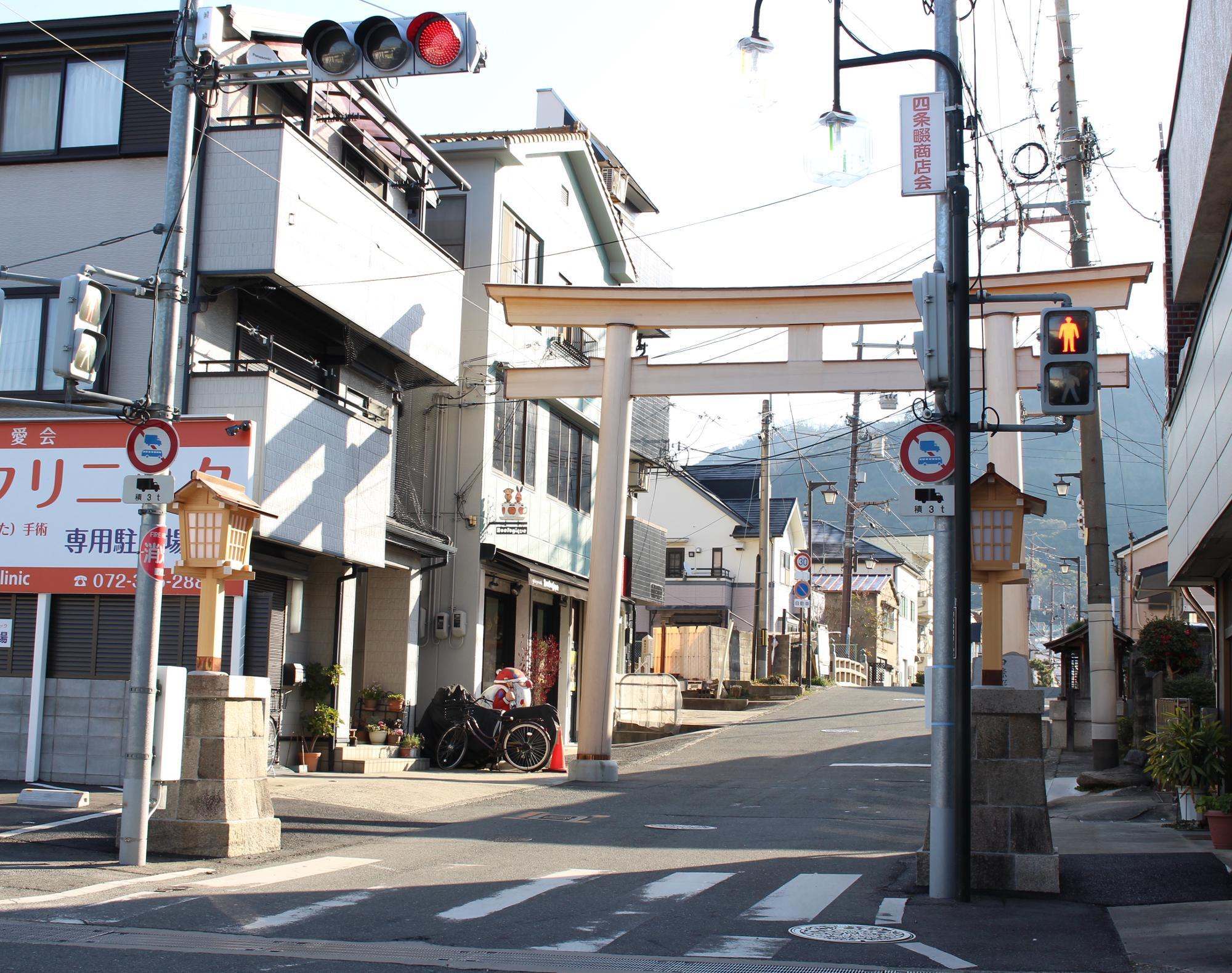 参道入口。信号機の後ろに再建された一対の灯ろう、その奥にあるのが一の鳥居