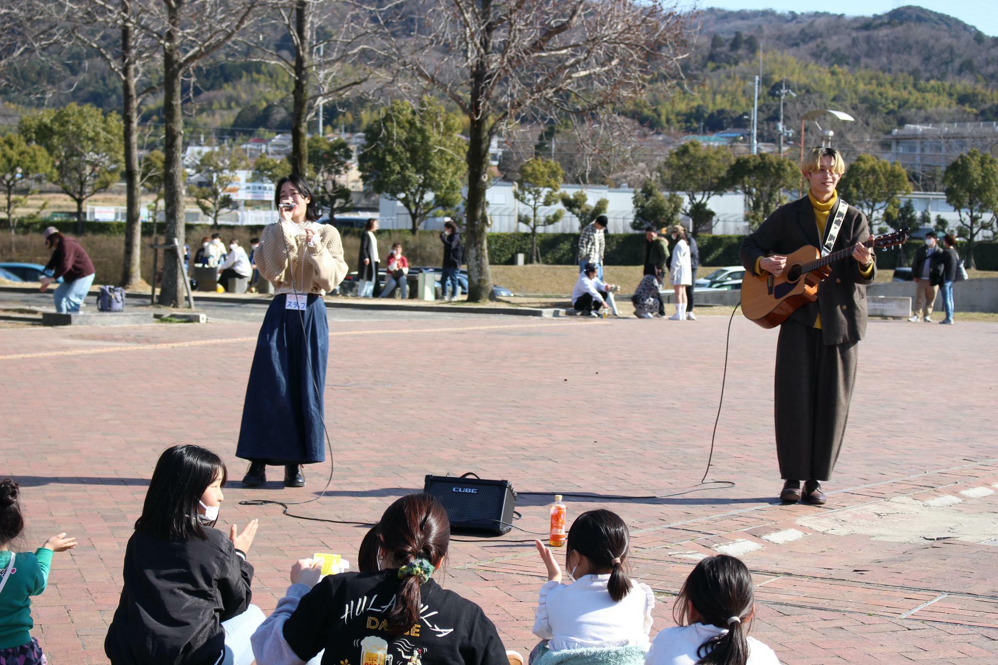 路上ライブ中の「シャルマン・ココ（通称シャルココ）」。左はボーカルの愛花さん、右はギターのしょーまさん。