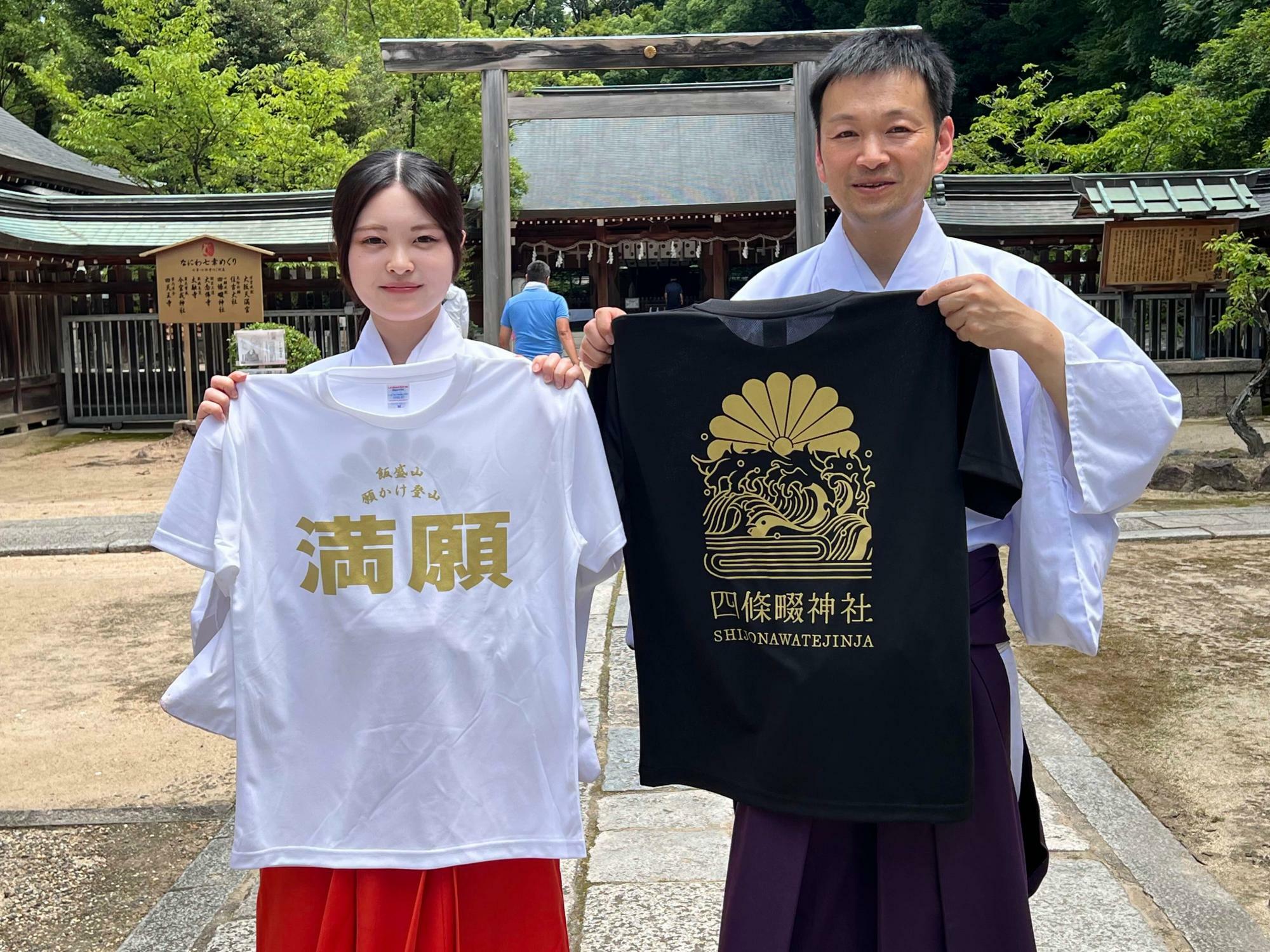 満願登山達成者に授与される記念品のTシャツ。大橋宮司（右）と巫女さんに撮影を手伝ってもらいました