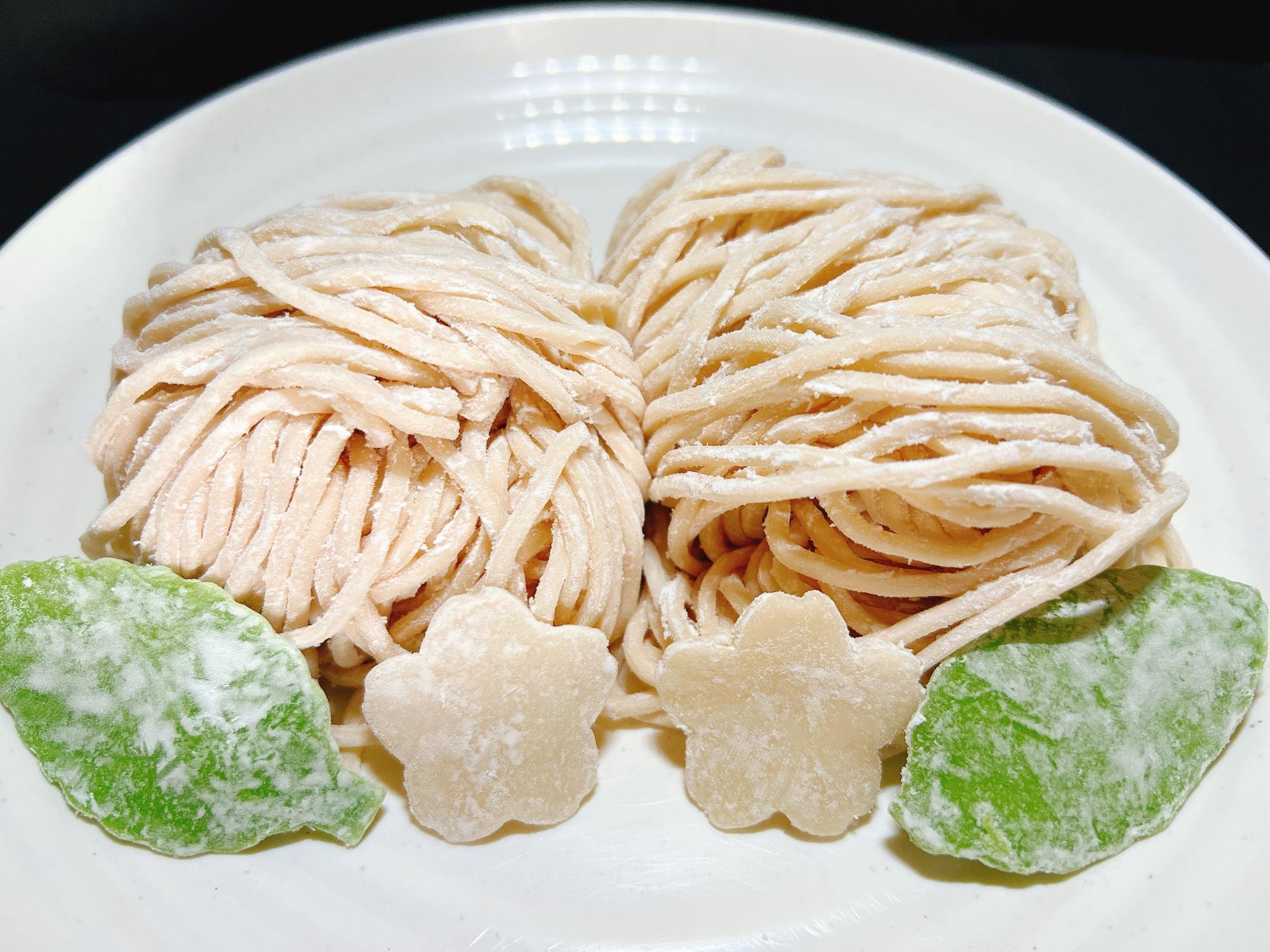 こちらは桜うどんで、桜の花びらと葉の形をした飾りも茹でて食べられるそうです（写真提供／株式会社サッポロめんフーズ 川越工場）