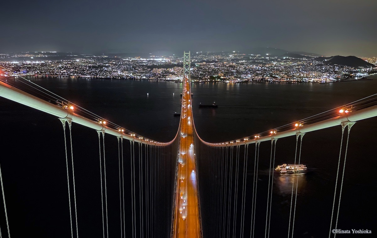 美しくライトアップされた「ルミナス神戸２」が、橋の下を通り過ぎていく 撮影協力 本州四国連絡高速道路株式会社