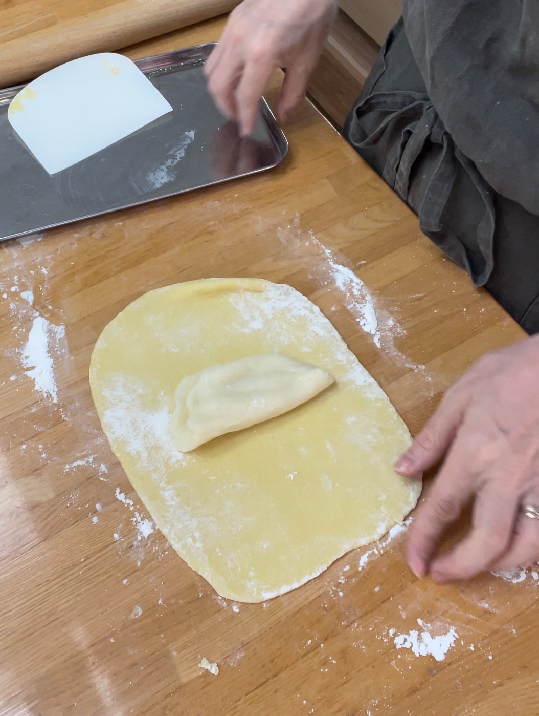 打ち粉し、木の麺棒で長方形に伸ばしバター風フィリングをのせて包み折り込み作業をする。