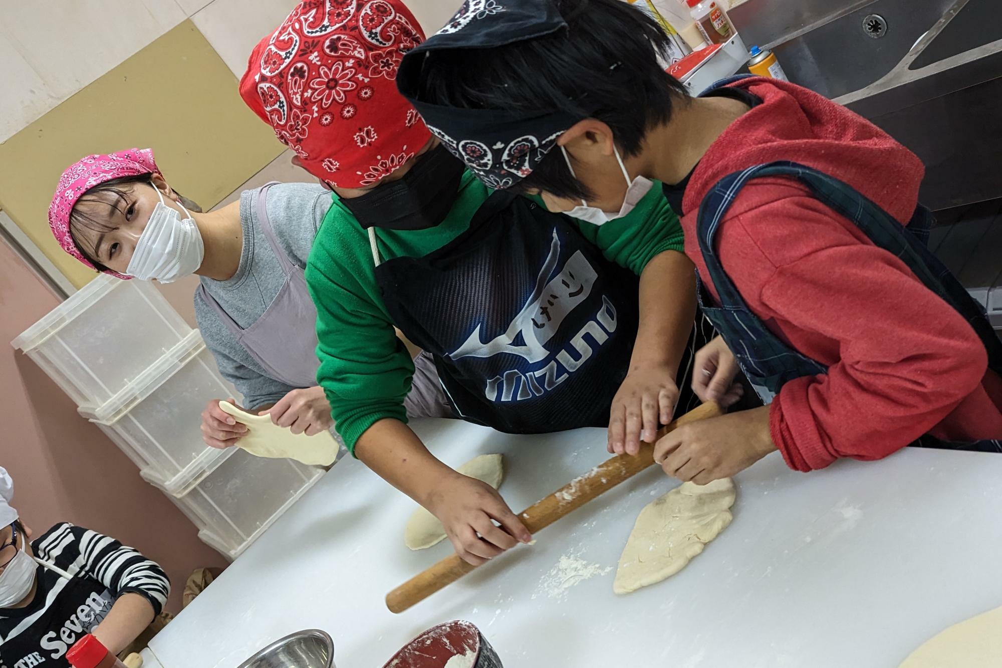小学生も大学生も初めてピザを作ったという人ばかり。粉をつけながら少しずつのばします。