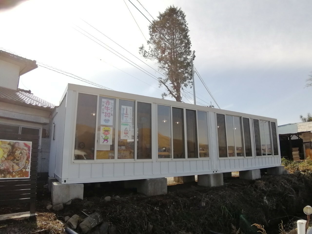 熊本高森線を熊本方面から右手、ガラス張りのコンテナハウスが目印