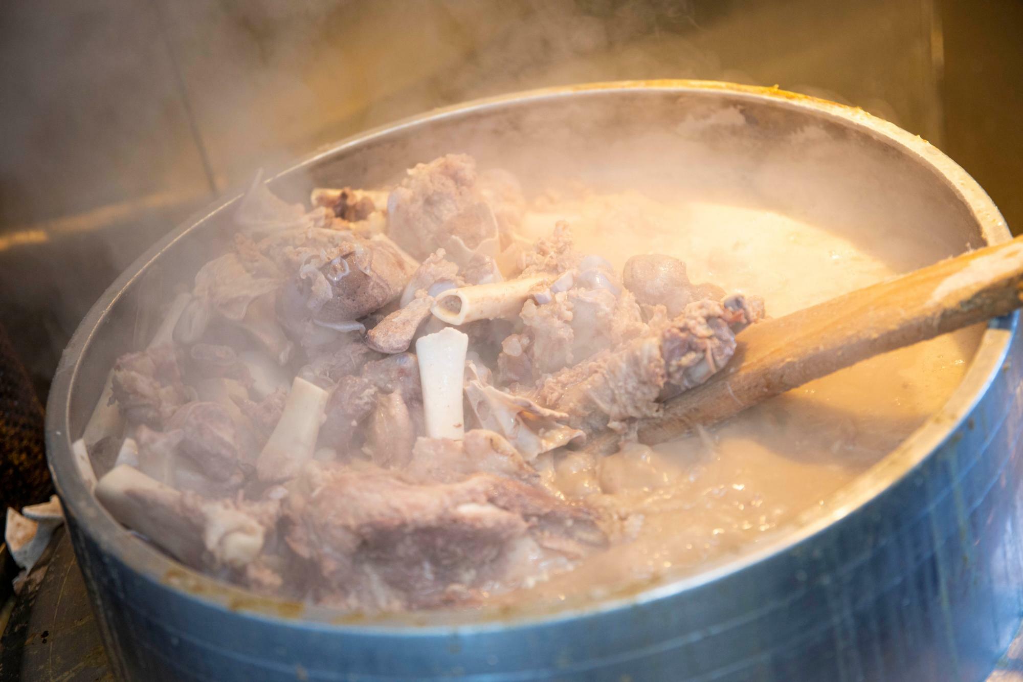 熱伝導のいい羽釜に、豚骨、豚足も加えてガッツリ炊き込む