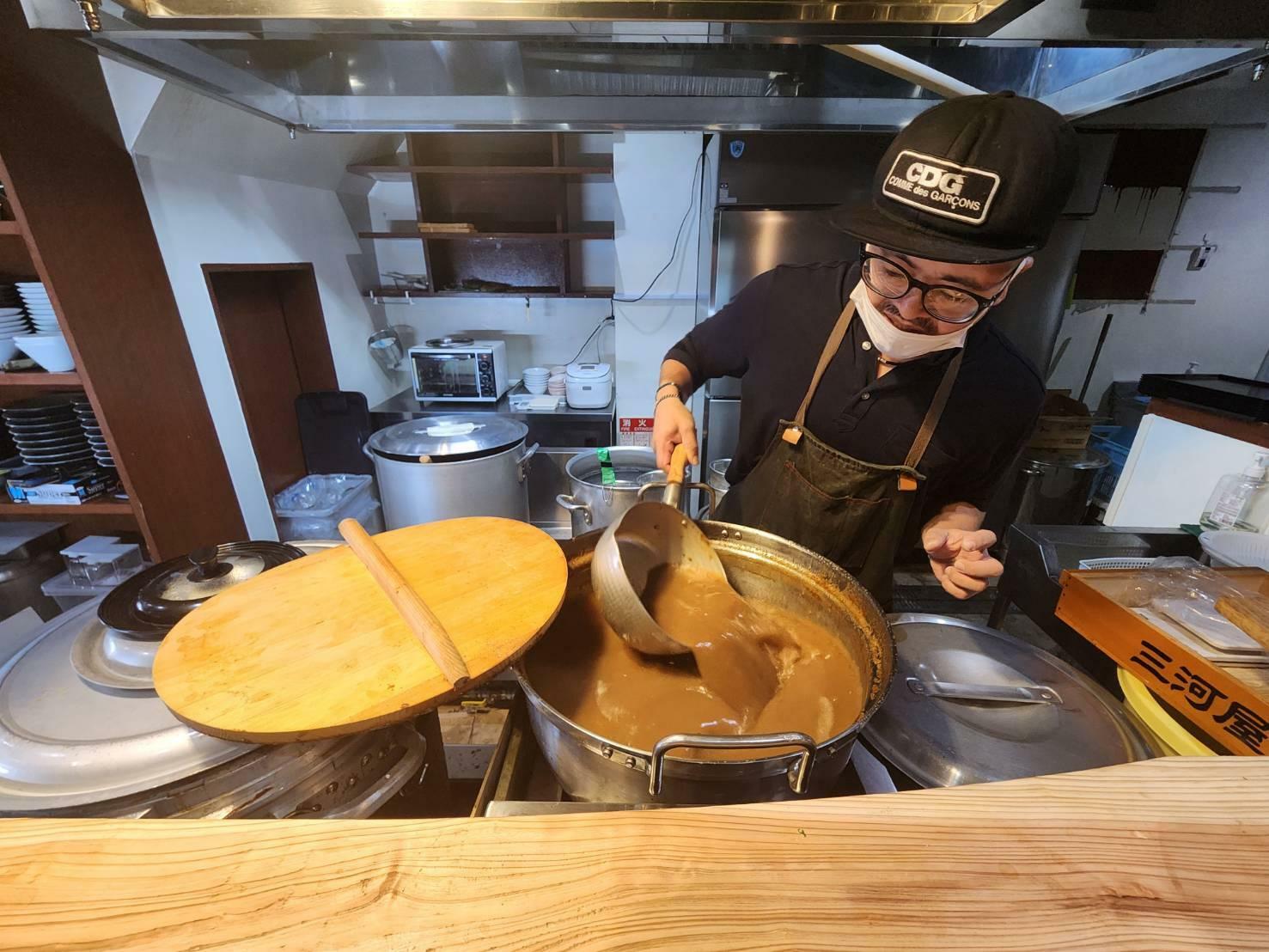 店主の髙尾野健蔵さん、肉系と乾物素材を一本炊きした茶濁スープを層ができないよう頻繁に混ぜ込む