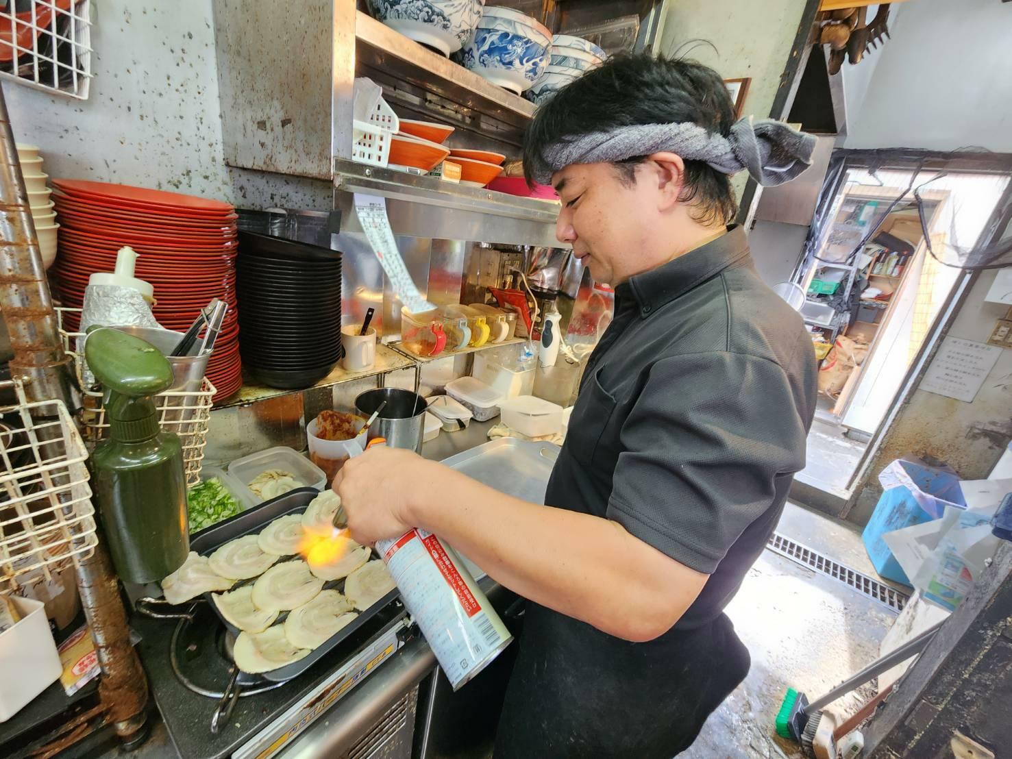 豚バラ肉に炙りを入れる柴田さん。遊び心に満ちた豚骨職人