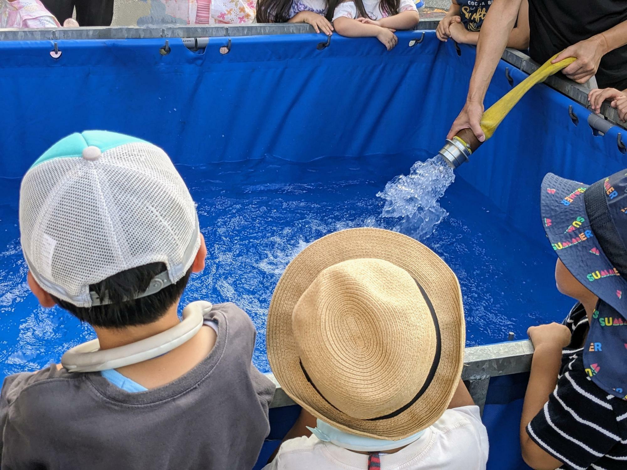 放水に使う水がたまるのを子どもたちが見つめています。