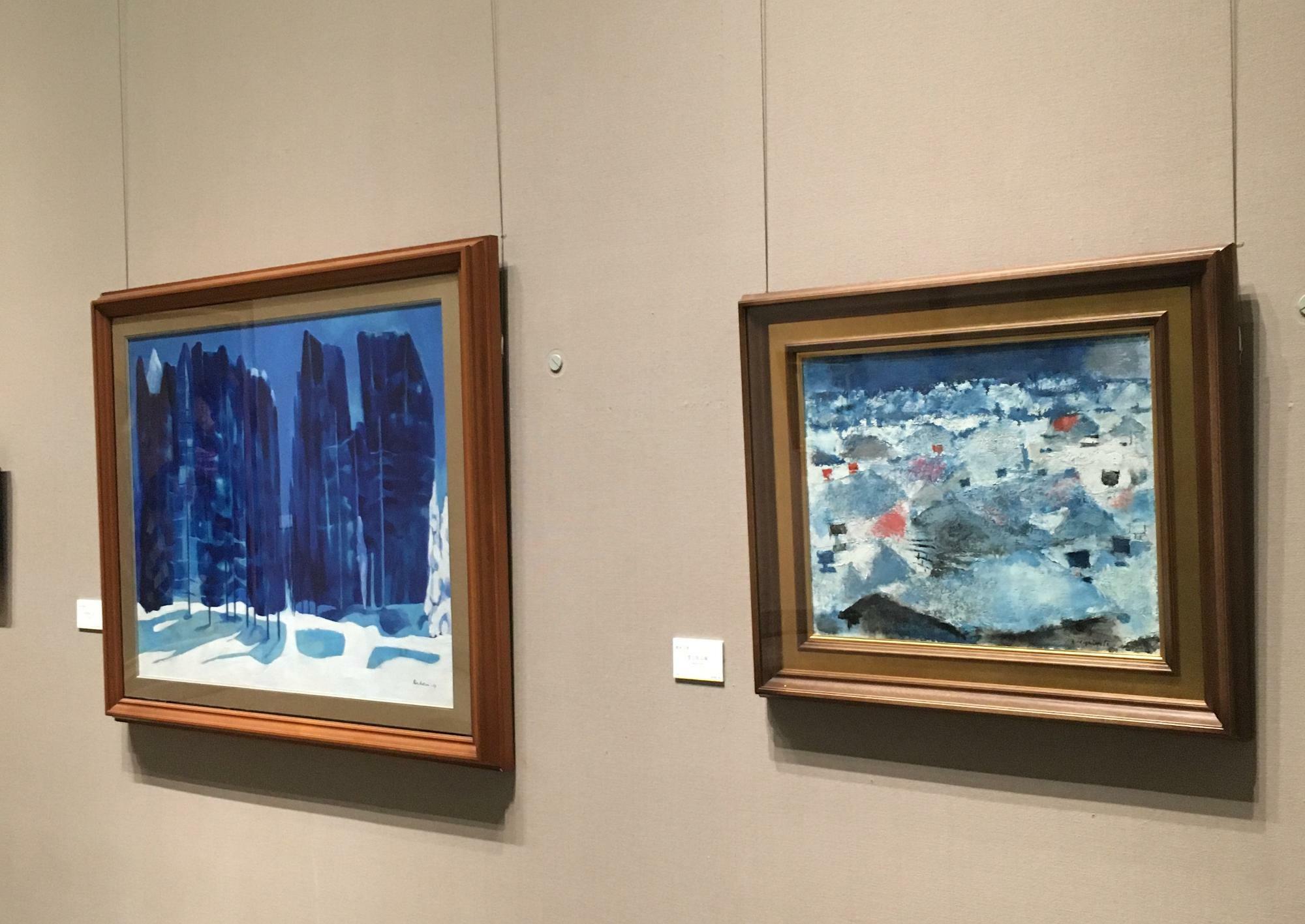 雪がテーマの絵画。左が小良氏の「防風林（1）」、右は橋本三郎氏の「雪と街工場」