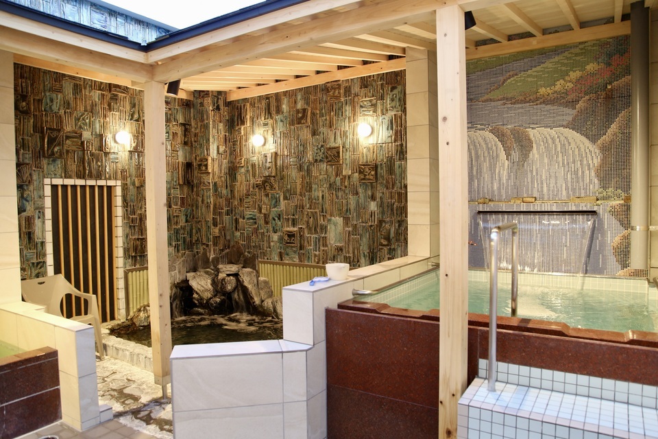 女湯の露天風呂は御影石やヒノキを用いたあたたかみのあるお風呂。 同じスペースに外気浴スペースがあります。