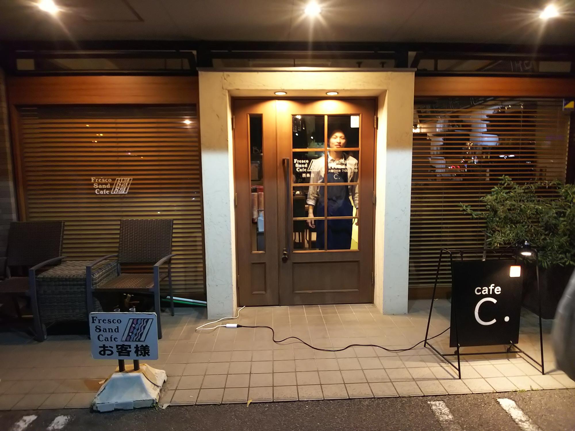 「cafe&bar C.」の外観。店内から顔をのぞかせるお茶目な店長明見さん