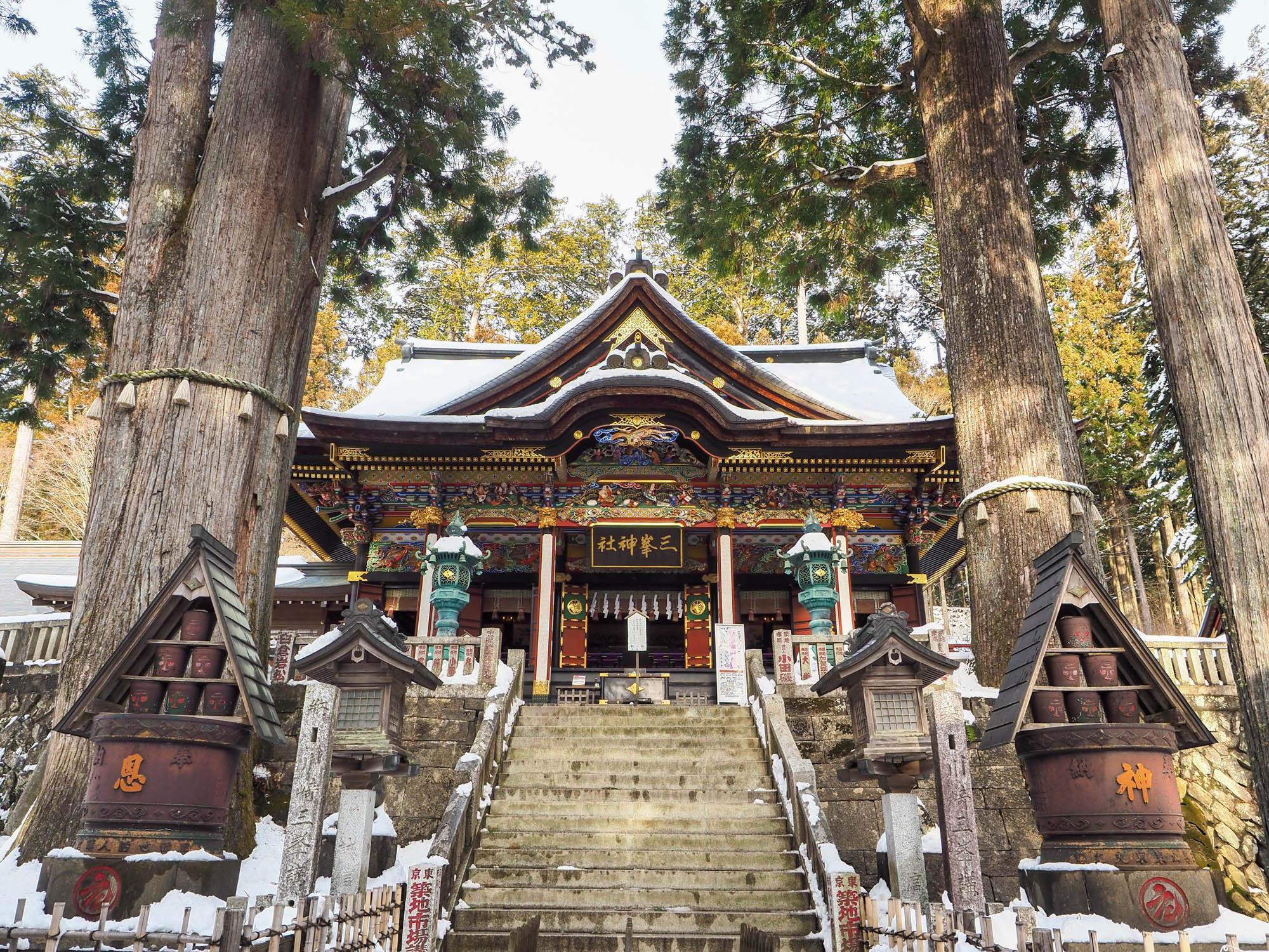 三峯神社。真白の雪に赤と黒を基調とする社殿が映える。