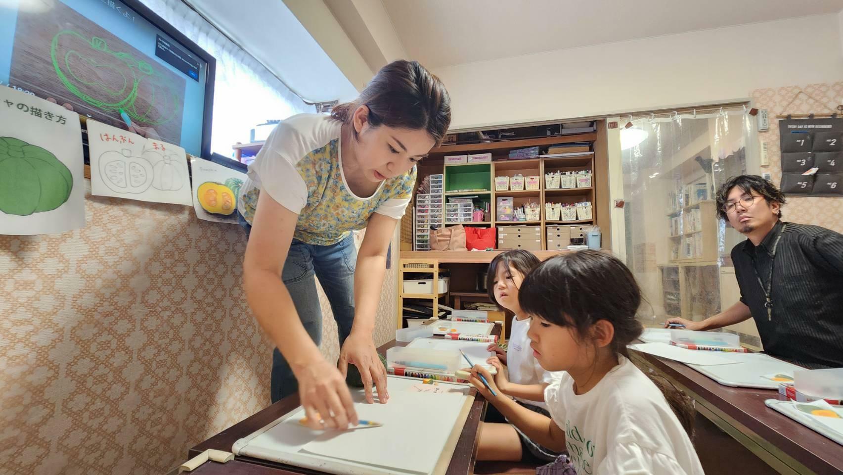 「こういうふうにしたらもっと上手く描けるよ」と子どもたちにアドバイスをする平賀先生