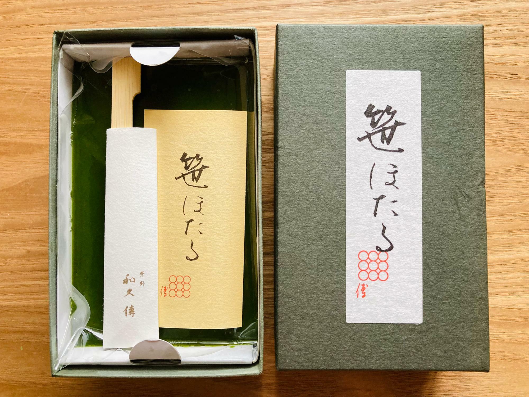 箱を開けると紙の箱に直接流し込まれた「笹ほたる」の生地が（左）。上から見ると緑色の抹茶の水ようかんしか見えませんが、取っ手を持ち上げて引き出して切ると、断面に美しいほうじ茶の琥珀羹が現れます。