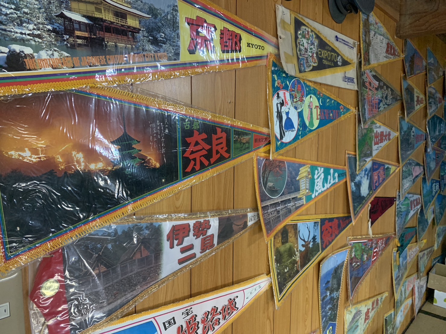 カフェスペースの壁に貼られた三角ペナントは、観光バスの運転手だった片山さんの父が全国を渡り歩きながら集めた品
