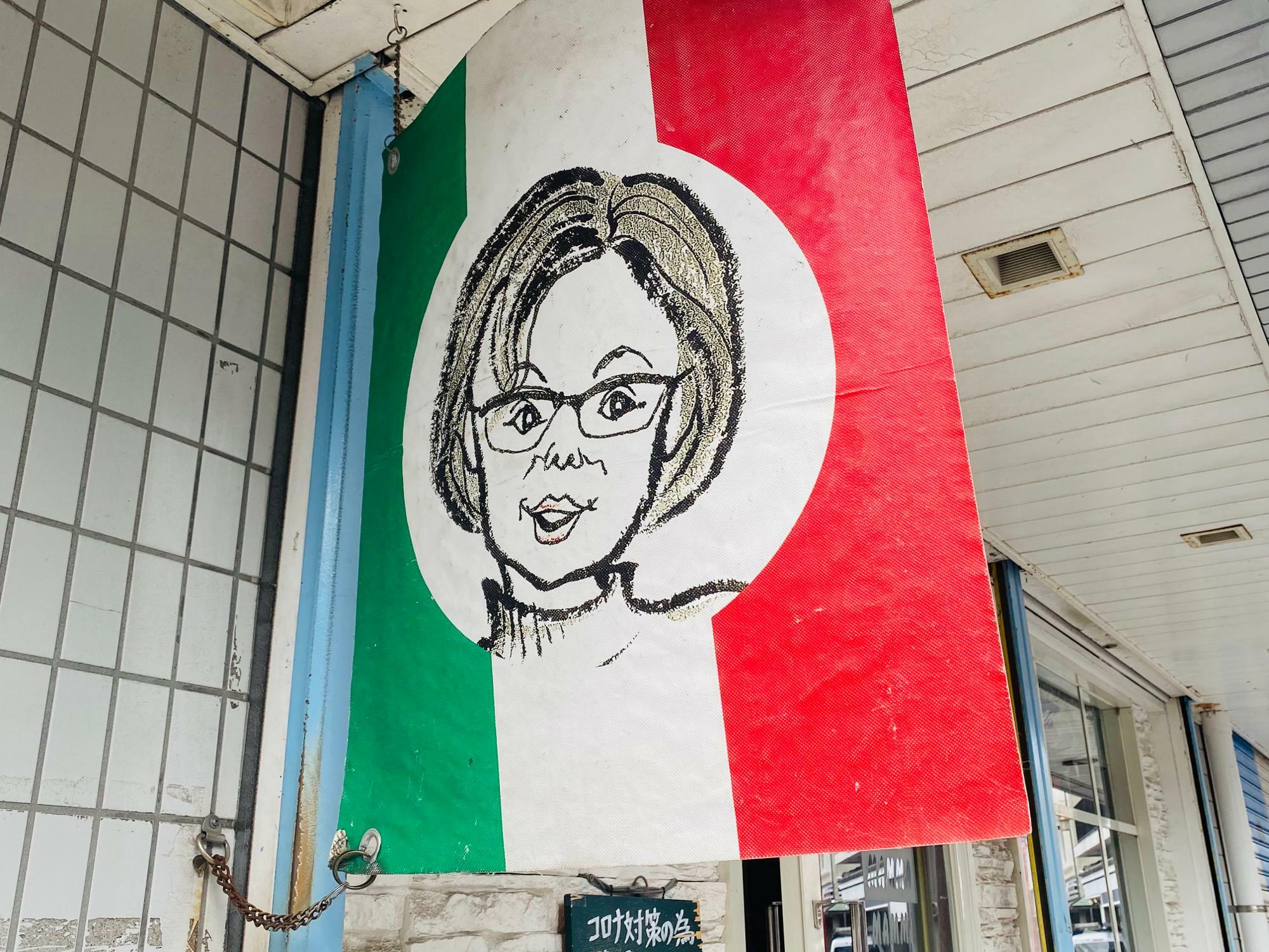 かわいいお母さんのイラストが描かれたイタリア国旗の看板