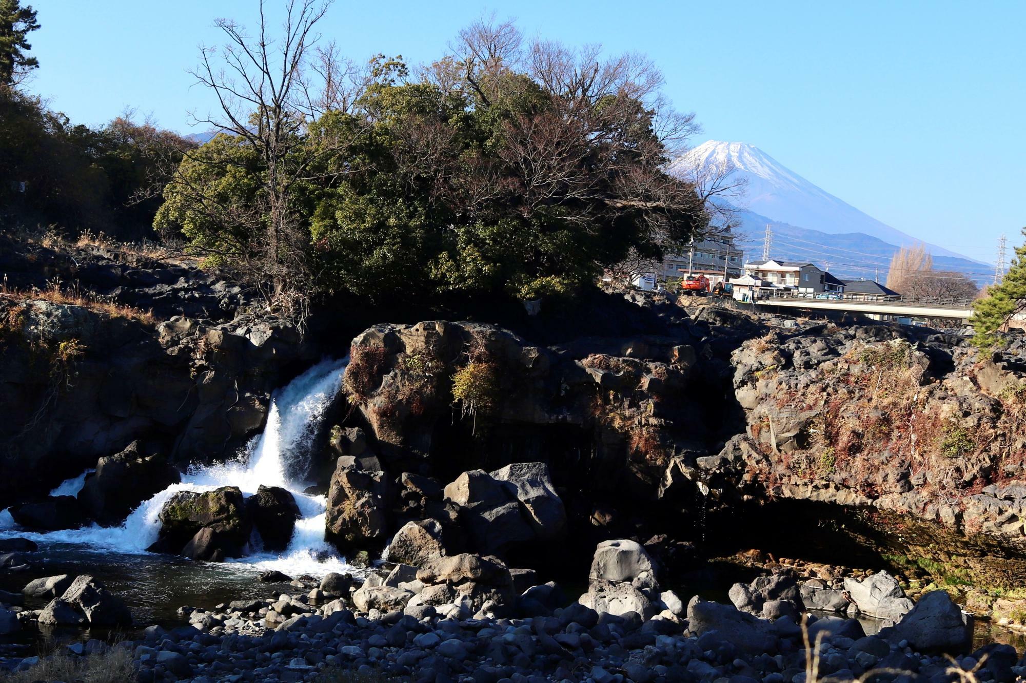 滝の流れの向こうにそびえる富士山