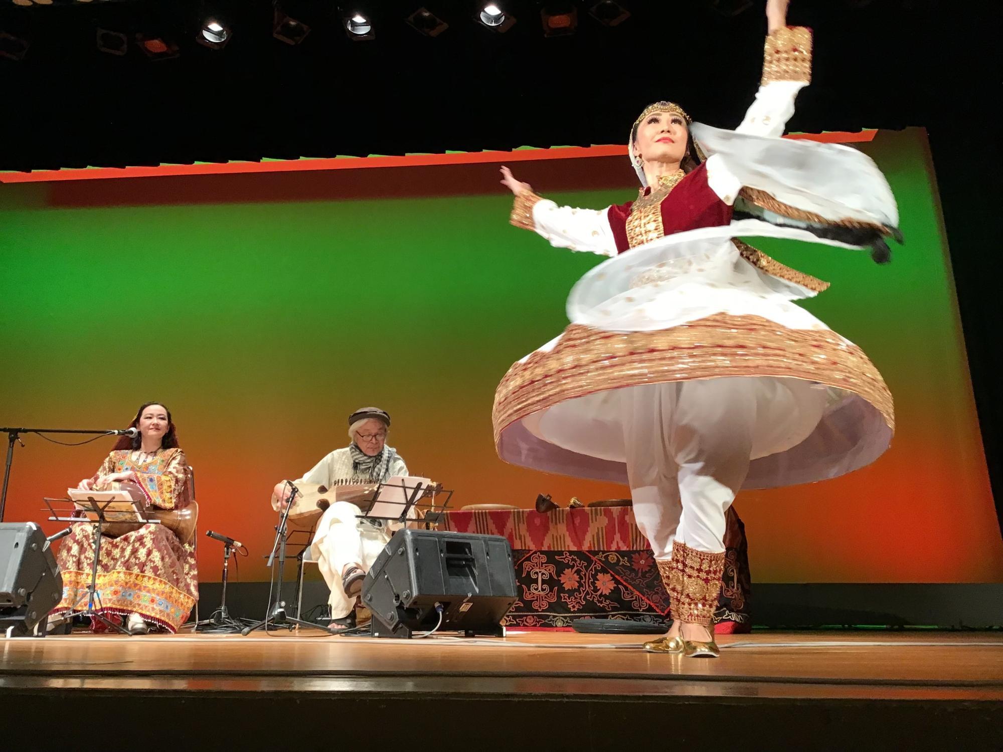 ドンバクを叩くやぎさん（左）とラバーブを弾く佐藤さん（中央）、曲に合わせて民族舞踊を披露する中央アジア・シルクロード舞踏団グリスタンのメンバーの方（右）