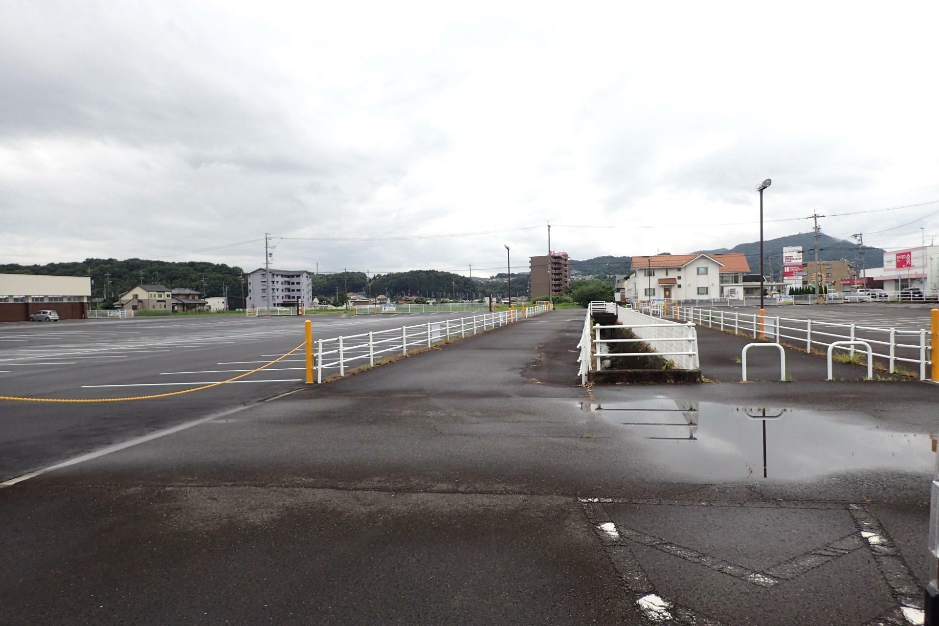 ゲンキー坂戸店の駐車場は、車道と水路が駐車エリアを分割するように通っています。