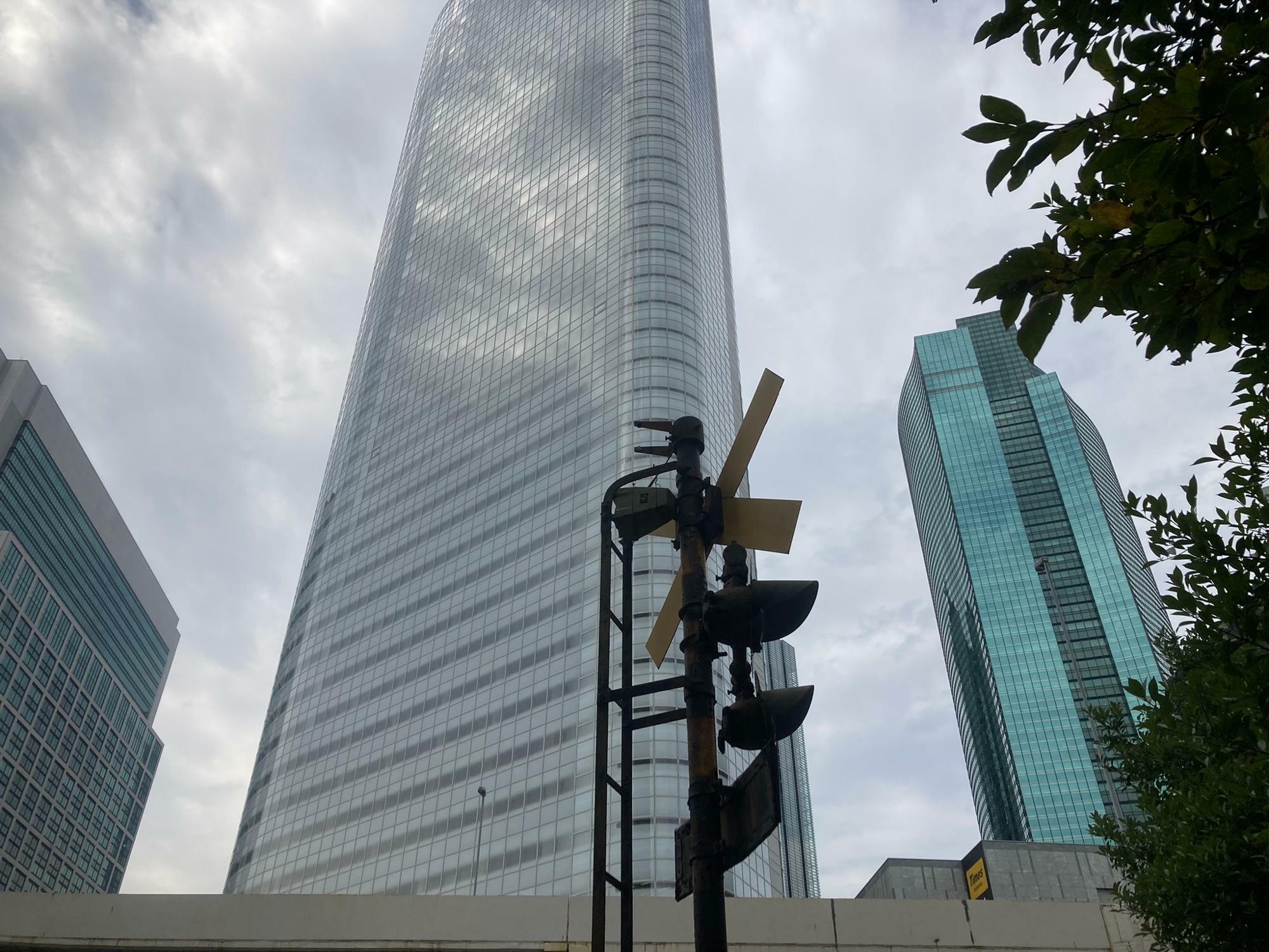 踏切警報機の背後にそびえるシオサイトの高層ビル