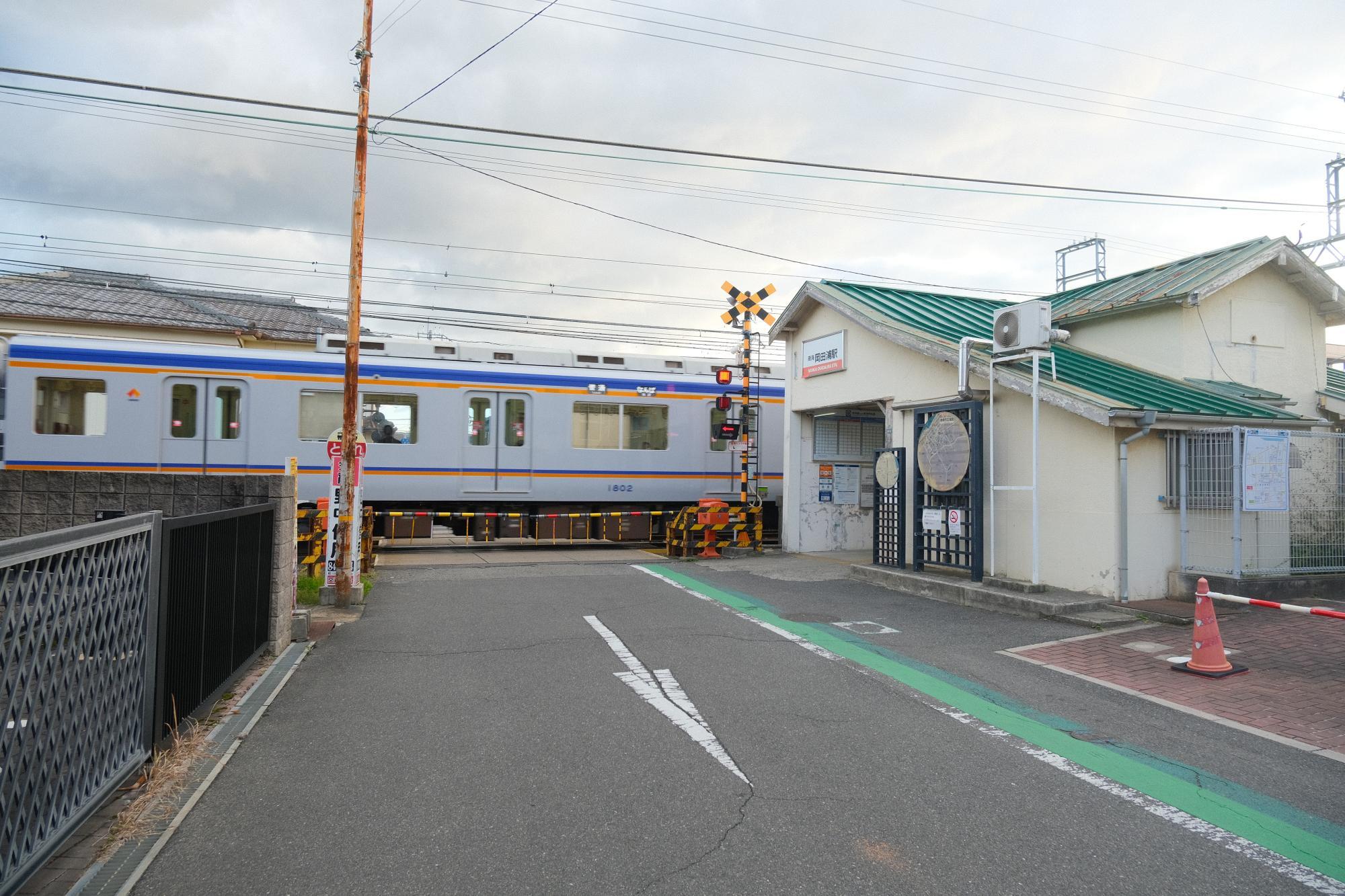 西信達小学校の正門から南西(山側)の方向に南海本線「岡田浦」駅が見える