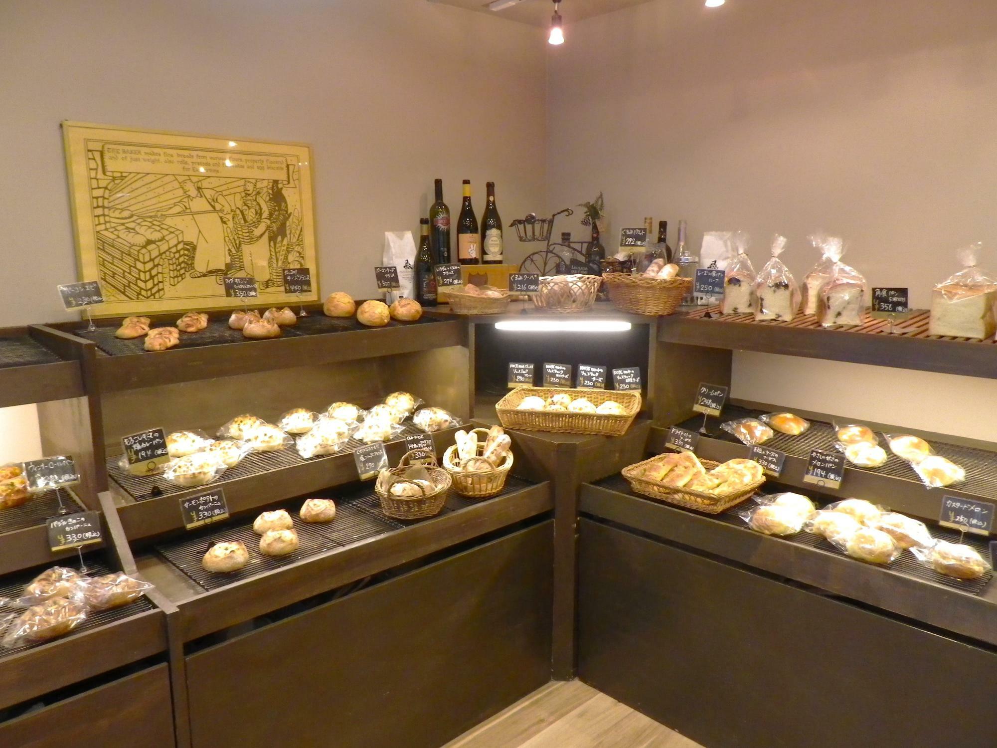 壁際に並んだシックなダークブラウンの展示棚にパンがいっぱい。