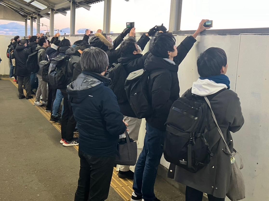 松岸駅跨線橋から初日の出と電車をカメラに収めようとする人々（筆者撮影）