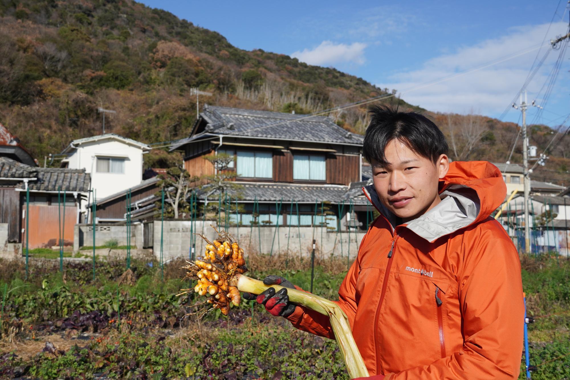 収穫したばかりのウコンを持つ、溝部光優さん