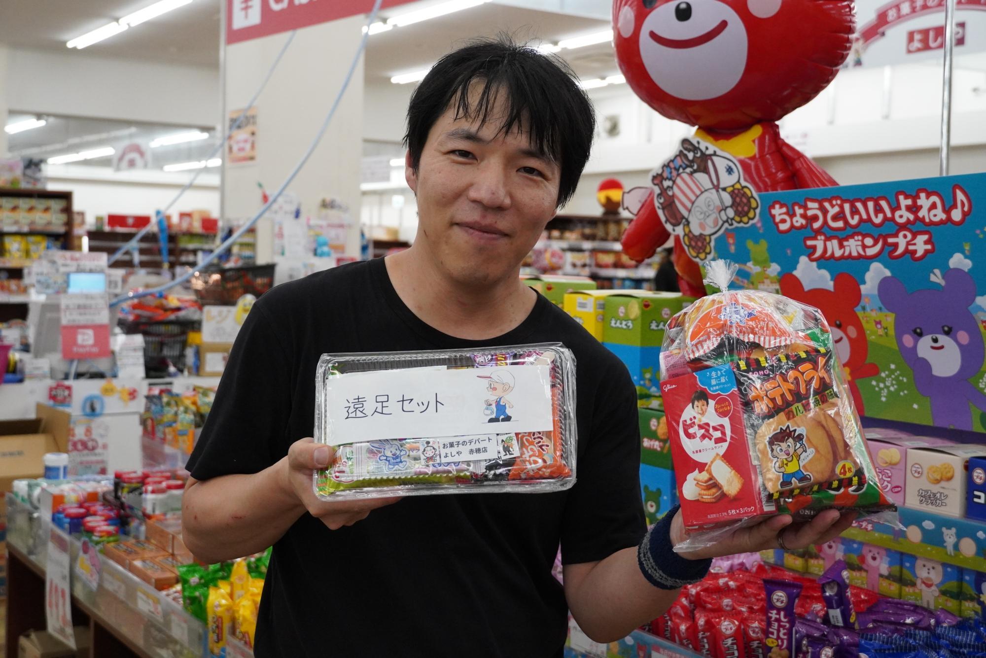 店長の岸哲也さんが持っている「遠足セット」300円、「お菓子のセット」400円～（写真は400円の袋）