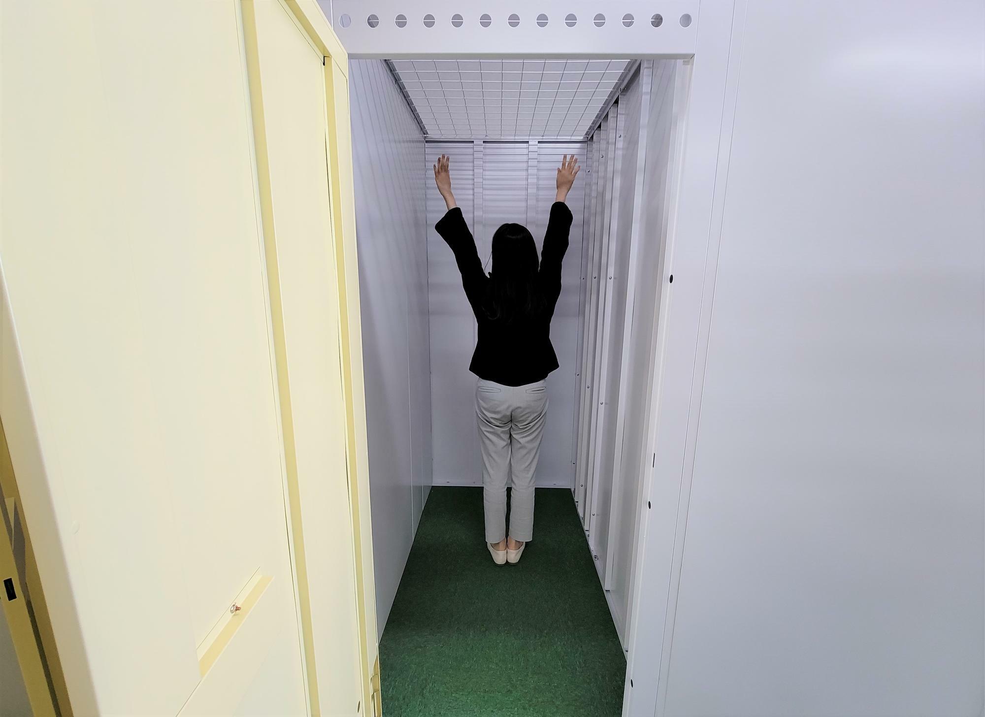 0.8畳サイズも天井が高いので、ラックなどで上手に仕切ればかなりの荷物が入る。写真の女性は、身長155センチ。昭和町店。