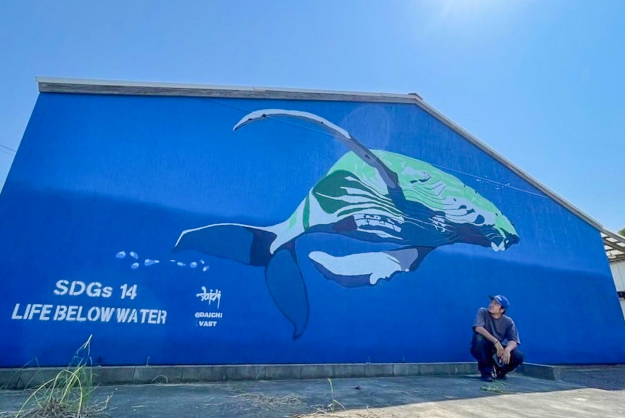 クジラの壁画と写るDAICHIさん（写真提供：DAICHI）