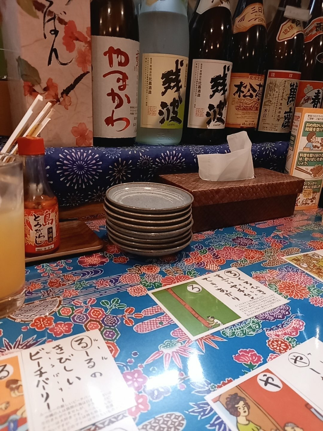 カウンターには泡盛の瓶が並んでいます。カウンターテーブルで沖縄方言を学びながら料理を待ちます