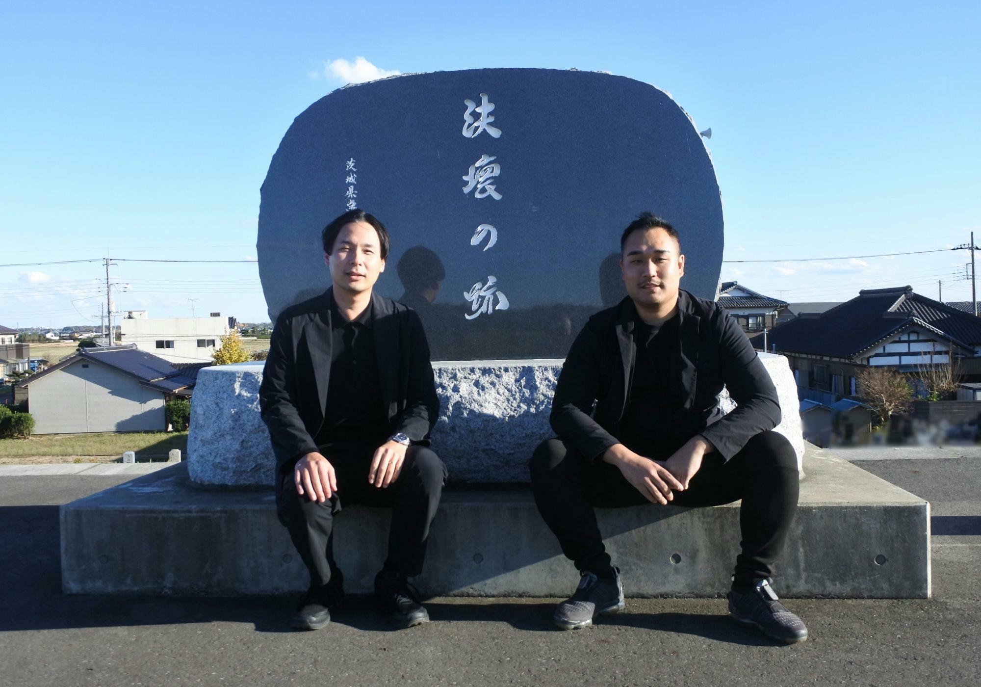 左：野村衛さん（第43代理事長）、右：高島伸明さん（まちづくり委員会委員長）　「決壊の碑」の前で