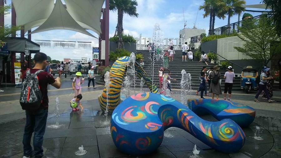 アートなオブジェの置かれた噴水では地元の子どもと観光客の子どもが一緒に遊ぶ