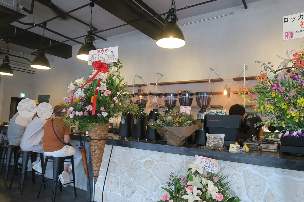 「rokkan COFFEE SHURI」のカウンター席。お祝いのお花がたくさん