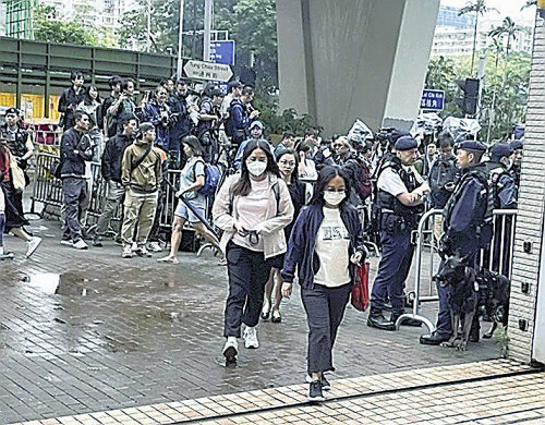 香港の裁判所で、警官が警戒する中、傍聴に向かう住民ら