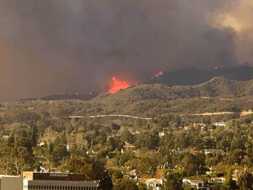 alt=ロサンゼルス西部で発生した山火事。燃え広がる炎と煙が空を覆う。