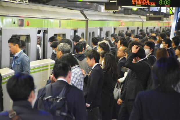 alt="ホームで満員電車を待つ人々と、隣に停車中のガラガラの女性専用車両"