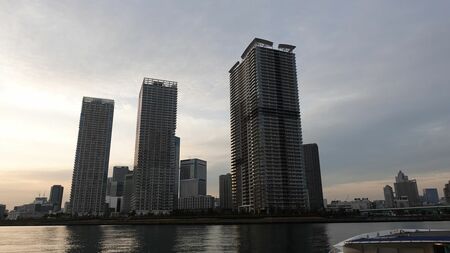 alt="東京都が推進する舟旅通勤の様子。高層ビル群を背景に、船が水路を進んでいる。"