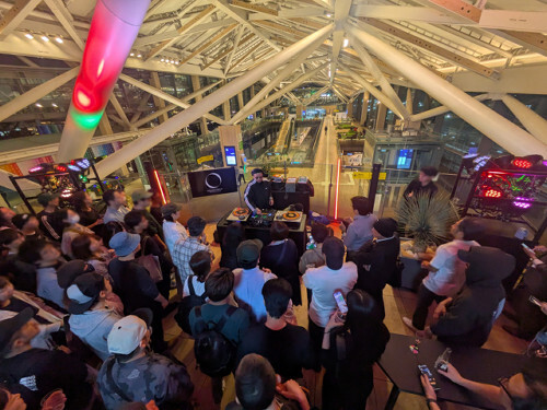 高輪ゲートウェイ駅「エキナカフライデー」イベントで、DJの音楽に合わせて踊る人々。駅コンコースがダンスフロアと化している様子。