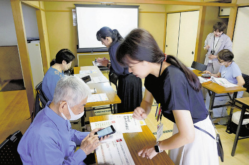 東京都練馬区のスマホ教室で、迷惑電話からの被害を防ぐ対策を学ぶ高齢者たち。専門家のアドバイスに熱心に耳を傾ける様子。