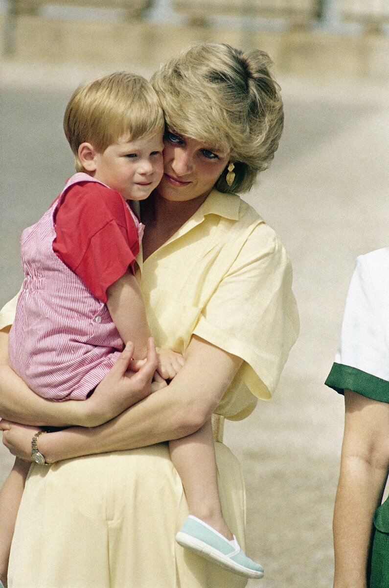1987年、スペインのマヨルカ島でダイアナ元妃に抱きかかえられる幼少期のヘンリー王子。母への強い思いが姓変更の背景に。