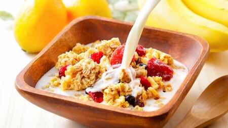 グラノーラに牛乳をかける様子。超加工食品とされるグラノーラは、ダイエットとの関連で注目されることも多い。