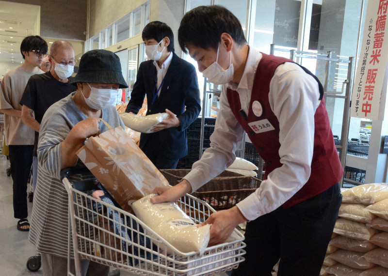 新潟市東区の原信店舗で、購入した政府備蓄米を受け取る買い物客。コメ価格高騰の中、安価な備蓄米が人気を集めている。