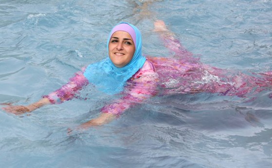 シリアの新しい服装規定導入を受け、ベルリンの露天風呂でブルキニを着用する若い女性の姿。公共の場で露出を控える服装の例示。