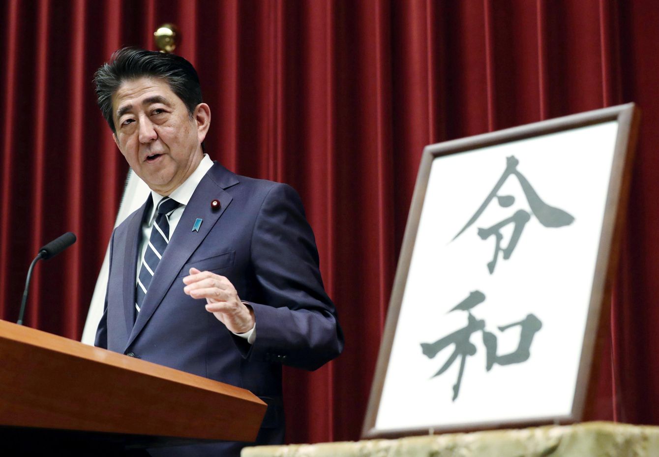 日本の報道の自由に関する議論の中で、新元号「令和」発表時の記者会見で談話を発表する安倍首相（当時）。権力とメディアの関係性が問われる一場面。